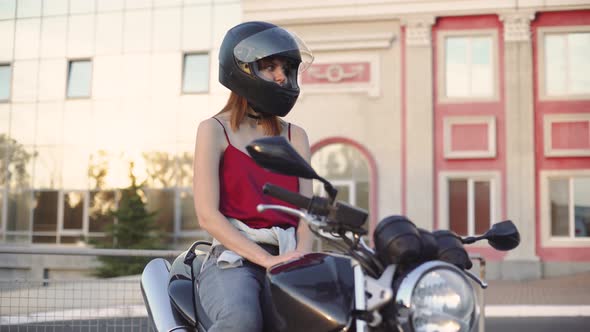 Beautiful Young Redhaired Woman Motorcyclist with Her Motorcycle and Helmet