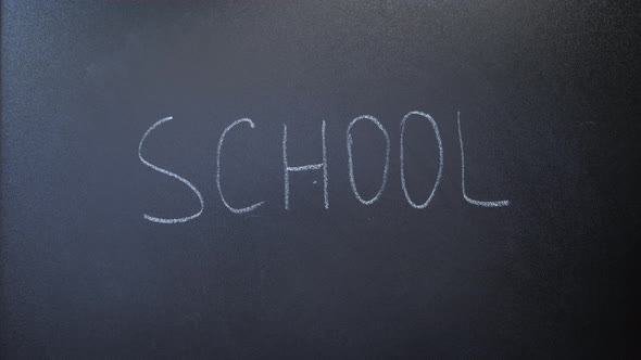 Word school written on chalkboard. Teacher writing word school with white chalk on blackboard