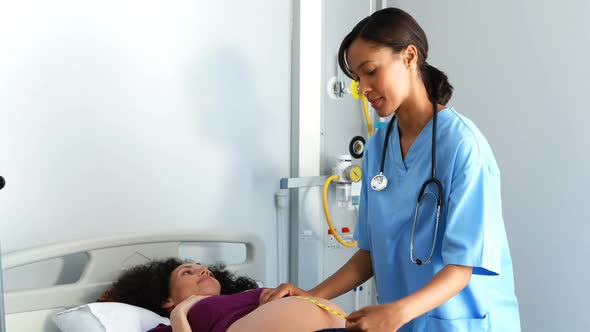 Doctor measuring pregnant womans belly in ward