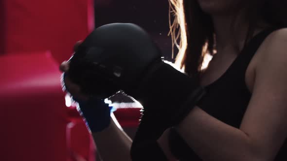 Young Woman Puts the Boxing Gloves on Her Hands