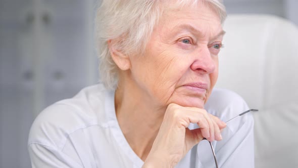 Senior wise grandmother with short grey hair holds glasses