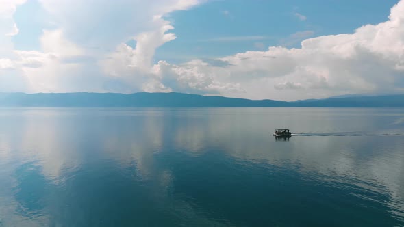 Boat going from right to left on very still blue water.