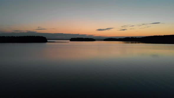 Aerial rising view tilting down, above a calm and peaceful lake, with a view of islands and reflecti