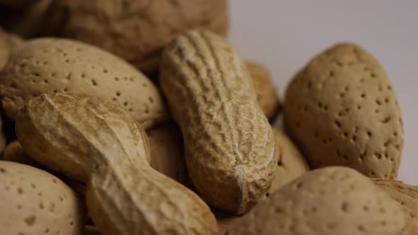 Cinematic, rotating shot of a variety of nuts on a white surface 