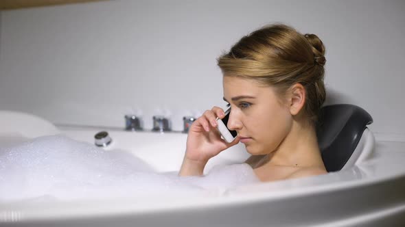 Upset Woman Talking Phone in Bath With Foam Bubbles, Negative News, Close-Up