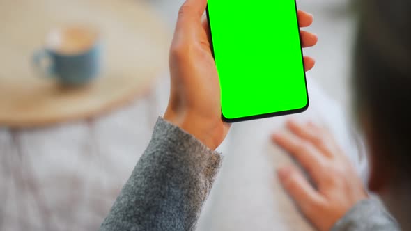 Woman at Home Using Smartphone with Green Mockup Screen in Vertical Mode