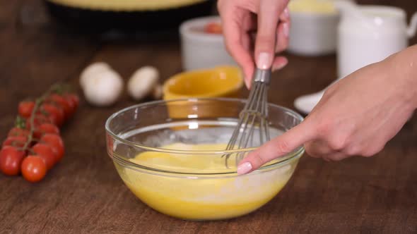 Whisking fresh raw chicken eggs in a glass bowl