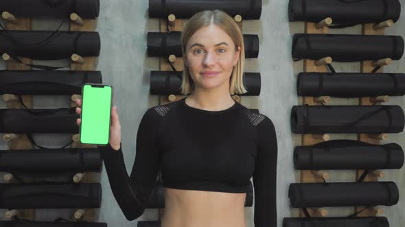 A Young Athletic Woman Holds A Smartphone in Her Hand, Shows A Green Chromakey Screen