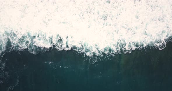 Overhead drone shot of sea wave on the beach. The sea water looks blue