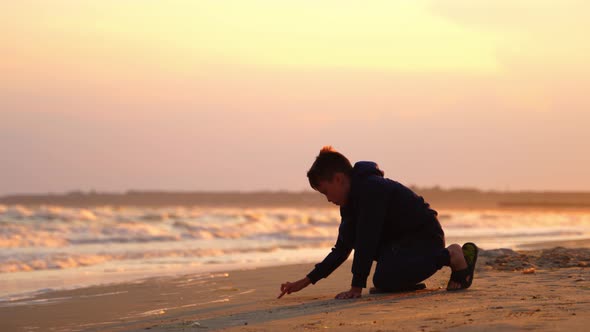 Boy drawing word on sand. Boy at the beach writing the word on the sand