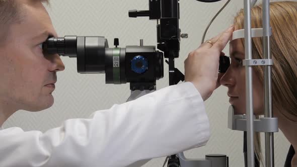 Doctor Looks at Patient's Eyes with a Microscope and Magnifier