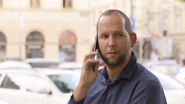 A Caucasian Man Talks on a Smartphone in an Urban Area  Closeup  a Colorful Street