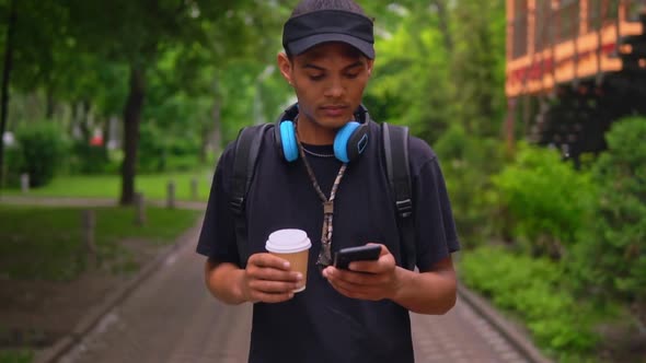 Young Man Using Mobile Walks in Summer City