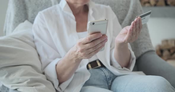 Closeup of a Mature Aged Female Client Using a Banking Credit Card and Mobile Phone