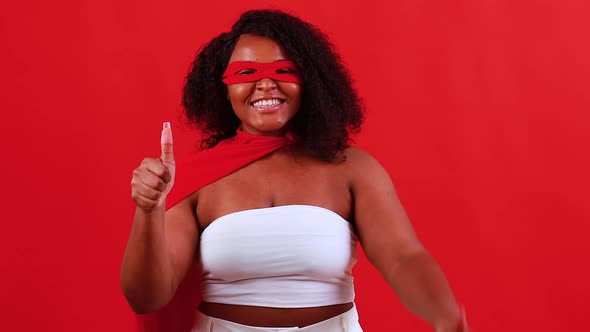 Latin Hispanic Woman in Red Eye Mask and Long Superhero Cloak in Studio Background