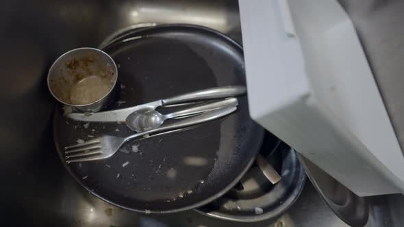 Close Handheld Pushout of Dirty Dishes in Metallic Kitchen Sink