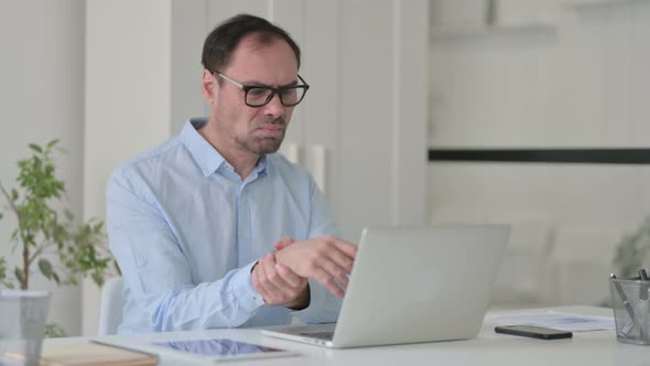 Middle Aged Man Having Wrist Pain While Using on Laptop