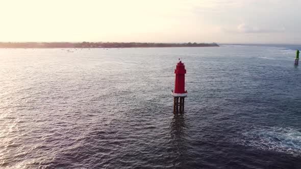 Red Lighthouse in the Ocean on Sunset