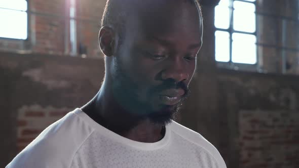 Portrait of black man in white t-shirt looking at camera indoors