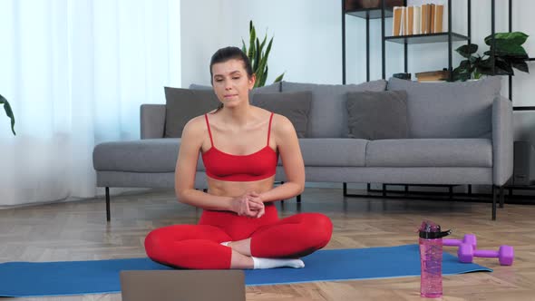 Camera Zoom in Woman Sits on Yoga Mat Listen Talk Fitness Trainer Study Online