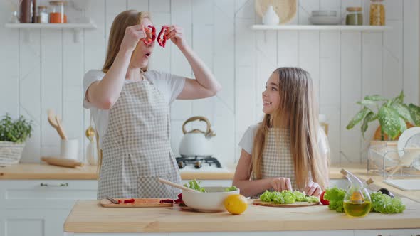 Daughter Teenager Girl Helping Mom with Salad in Kitchen at Home Cuts Lettuce Adult Mother with Long