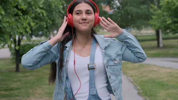 Cheerful Beautiful Girl in Red Headphones Goes To Skip and Listens To Music