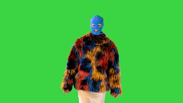 Caucasian Girl in Balaclava and Multicolored Fur Coat Walks on a Green Screen Chroma Key