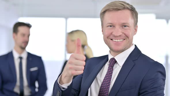 Portrait of Cheerful Businessman Showing Thumbs Up in Office 