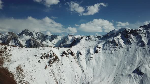 Huge mountains covered with snow. Panorama of the mountain peaks, blue sky with white clouds