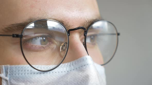 Close-up of a Man wearing Glasses and a Mask Looking Away and Talking during a Virus pandemic