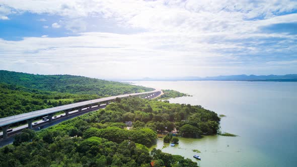 time lapse of beautiful expressway in a green forest with a dam on the side.