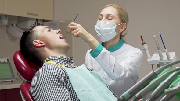 Female Dentist Examining Teeth of Her Patient, Working at Dental Clinic