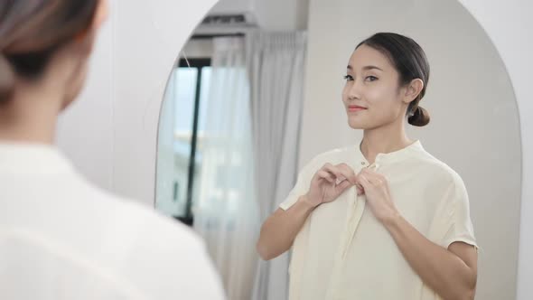 Asian woman happily dressed in front of the mirror She looks good and has confid