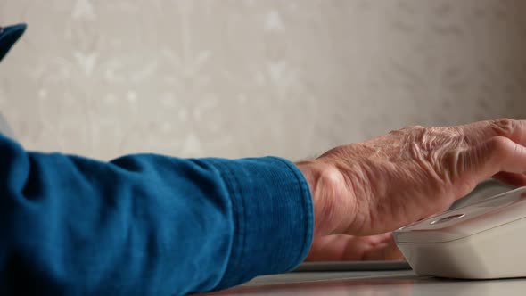 An elderly man measures blood pressure with a home portable blood pressure monitor. Health care in o