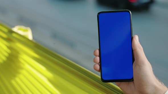 Close Up of Male Hand Holding Smartphone with Blue Screen