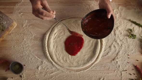 Chef Spreading Tomato Sauce on Pizza