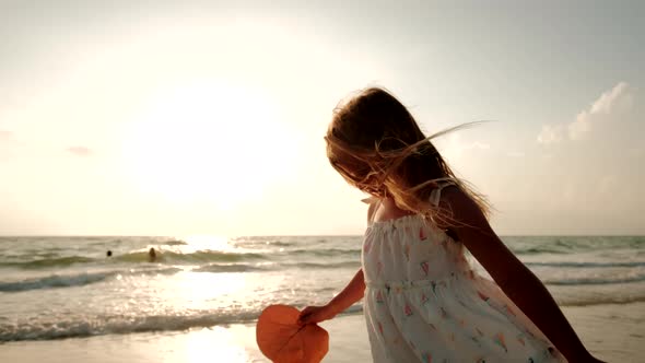 A Little Girl in a White Dress Walk Along the Beach