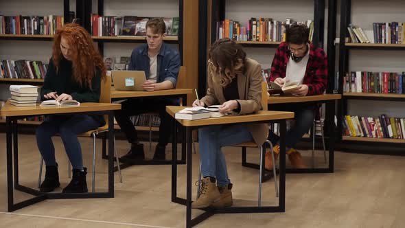 Group of Students Preparing for Exam in University Library Two Beautiful Females Making Notes Two