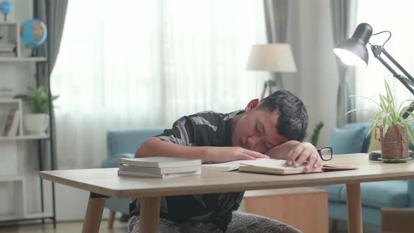 Tired Teenage Boy Sleeping On The Table At Home After Doing Home Work