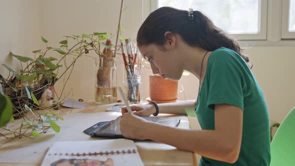 Teenage girl drawing using a tablet computer and an electronic pen