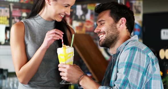 Happy couple interacting while having milkshake