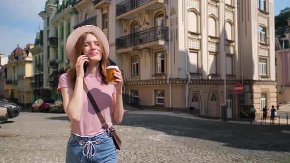 Beautiful Young Woman Tourist with Takeout Coffee in the City Center Talking on the Phone