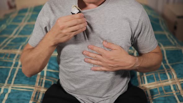 Male Patient Checks His Holter Cardiac Monitor During Quarantine