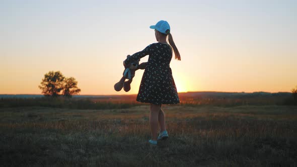 Little Girl in Dress Holding Teddy Bear Toy at Sunset. Concept of a Child Dream