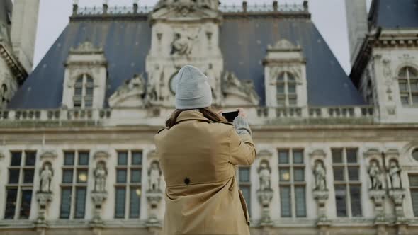 Young woman in a gray hat makes a picture on the phone in Paris in autumn
