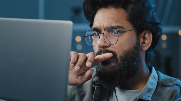 Focused Arabian Indian Bearded Man Freelancer in Eyeglasses Working on Computer at Home Late Night