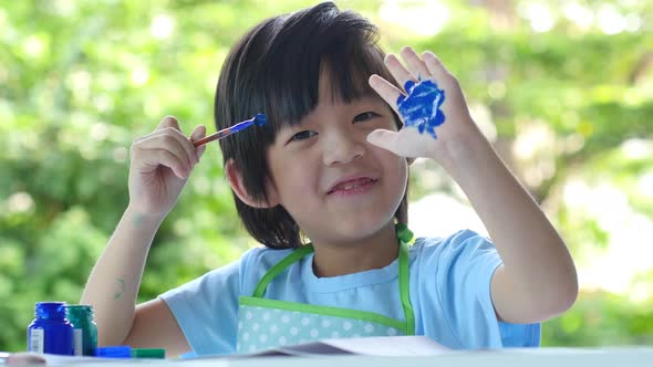 Cute Asian Child Enjoying Arts And Crafts Painting With His Hand