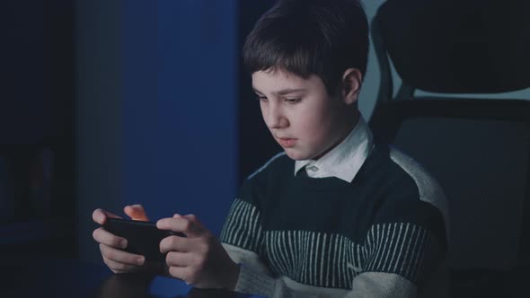 Portrait of Handsome Boy Playing Video Game with Smart Phone Indoors