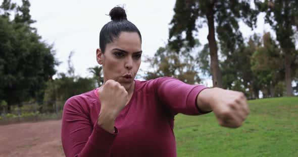 Curvy woman doing boxing exercises at park - Sport and workout concept
