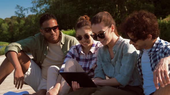 Friends with Tablet Pc on Pier at Lake or River